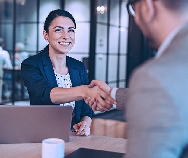 Man and woman shaking hands over conference table