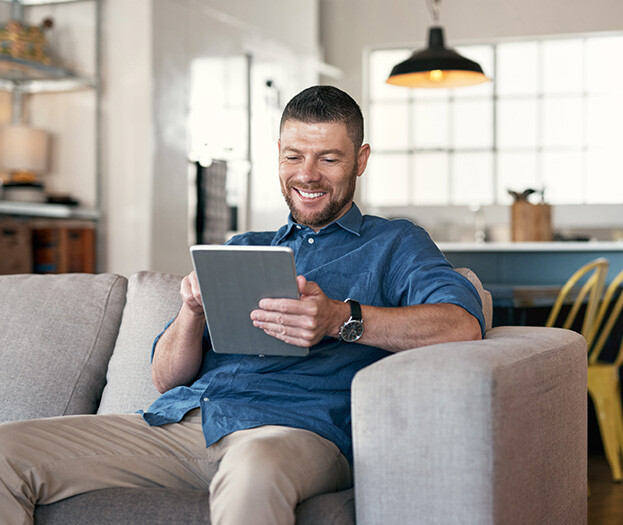 Smiling man siting on couch with tablet device