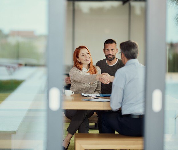 Two people shaking hands across a conference table